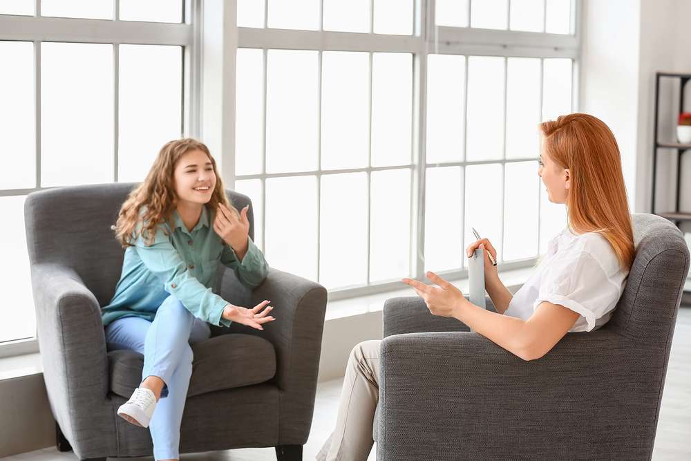 Psychologist working with teenage girl in office
